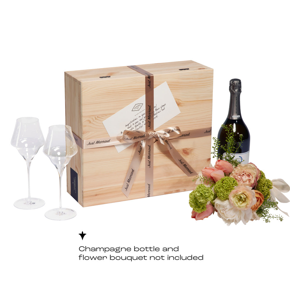 A wedding gift set from Josephinenhütte featuring a wooden box with a "Just Married" ribbon and a congratulatory card. The set includes two JOSEPHINE No 4 champagne glasses. The champagne bottle and flowers are not included.